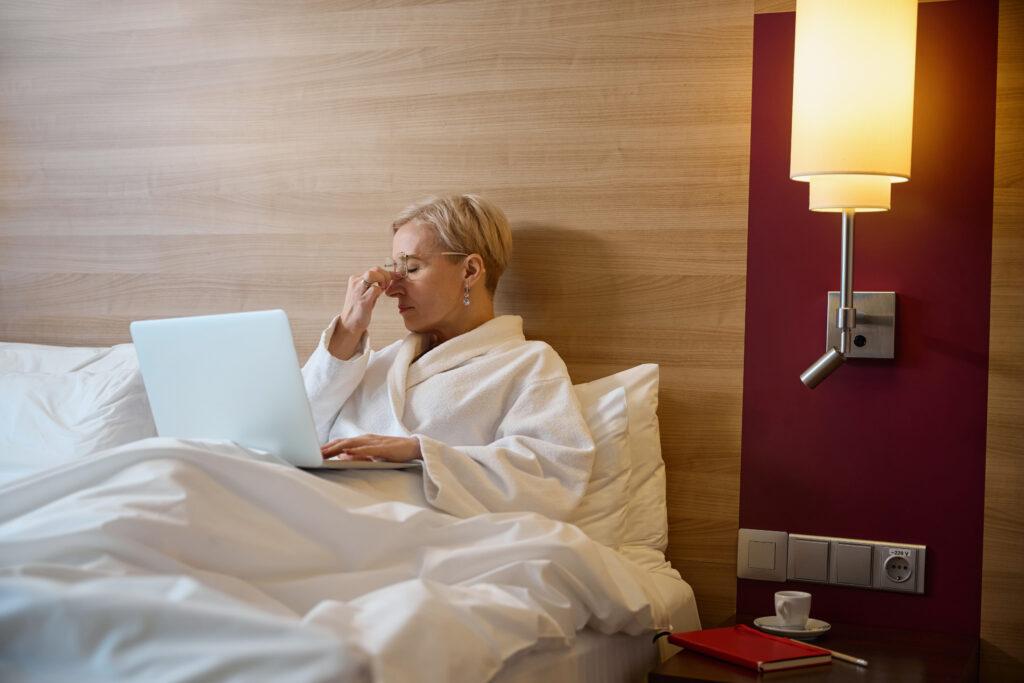 Geschäftsreise - Frau arbeitet im Bett